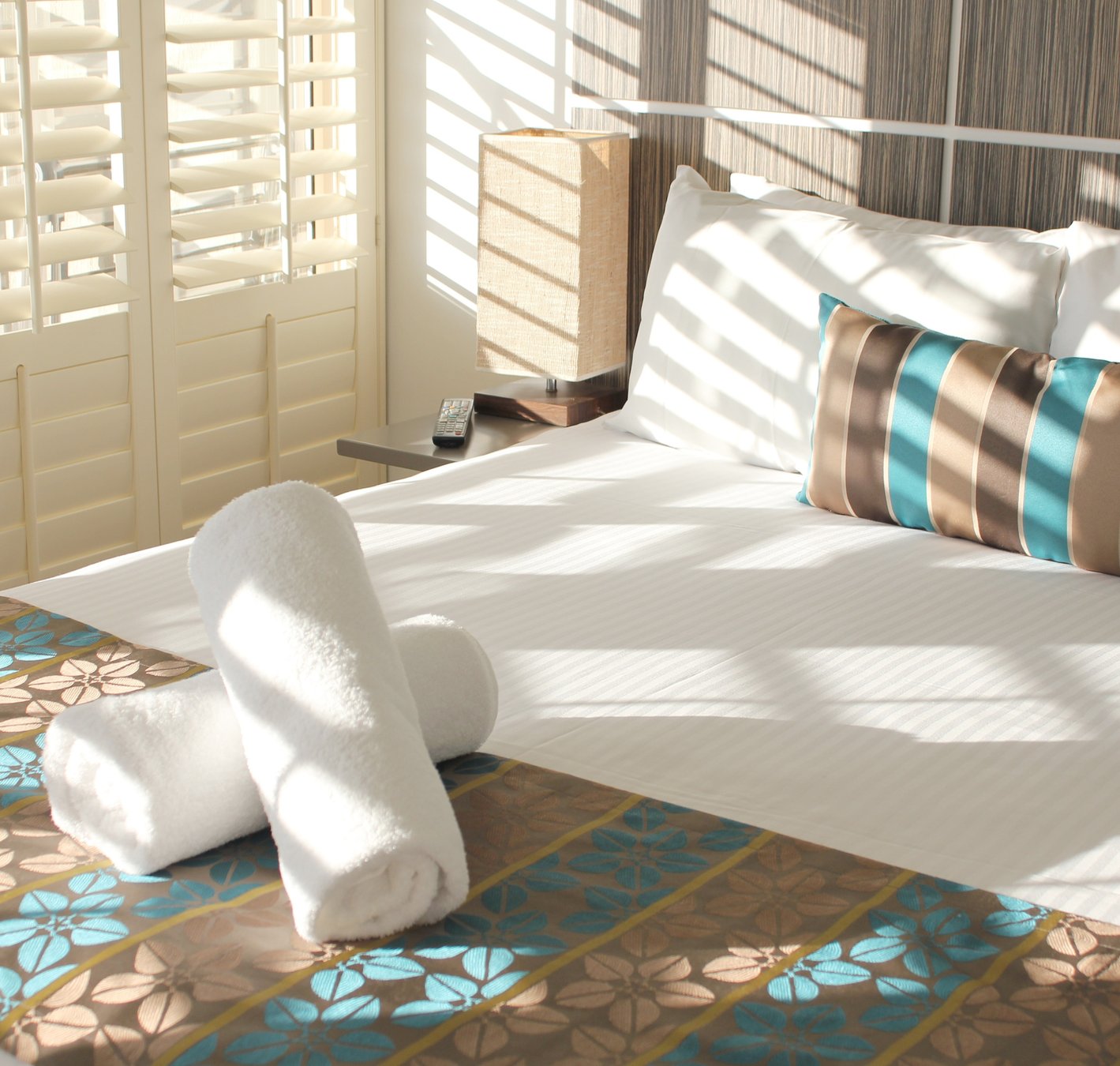 Sunlit resort bedroom with rolled towels