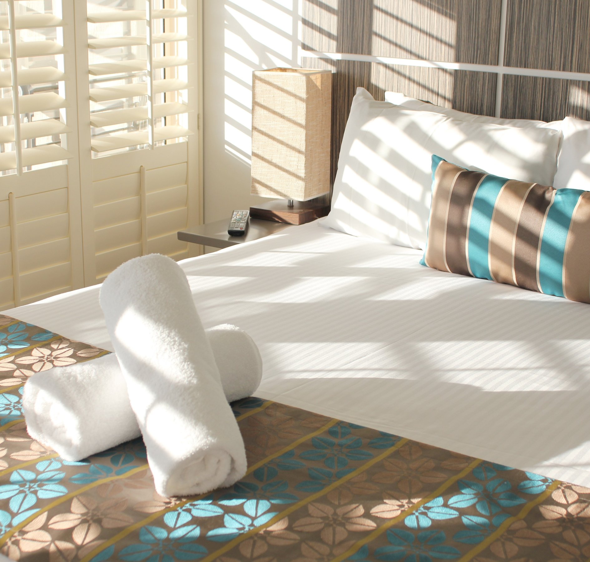 Sunlit resort bedroom with rolled towels