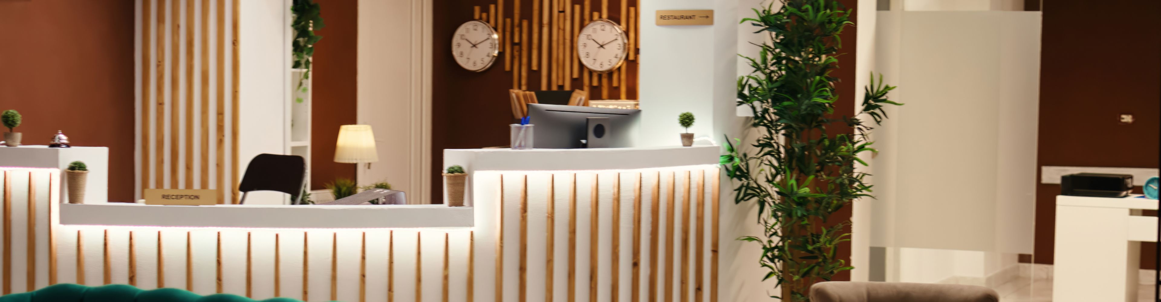 Hotel reception desk with plants and wall clocks