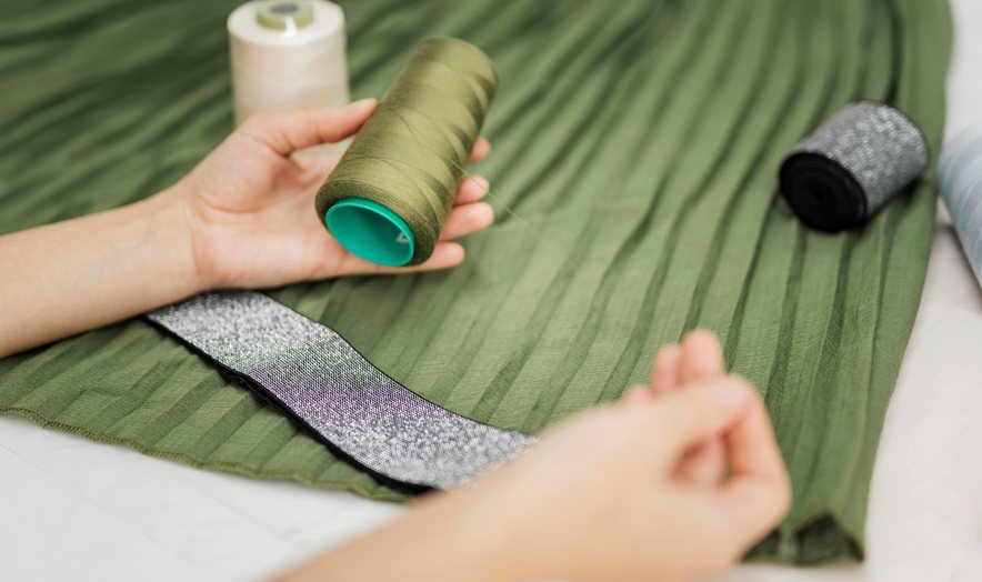 Hands working with thread on green fabric