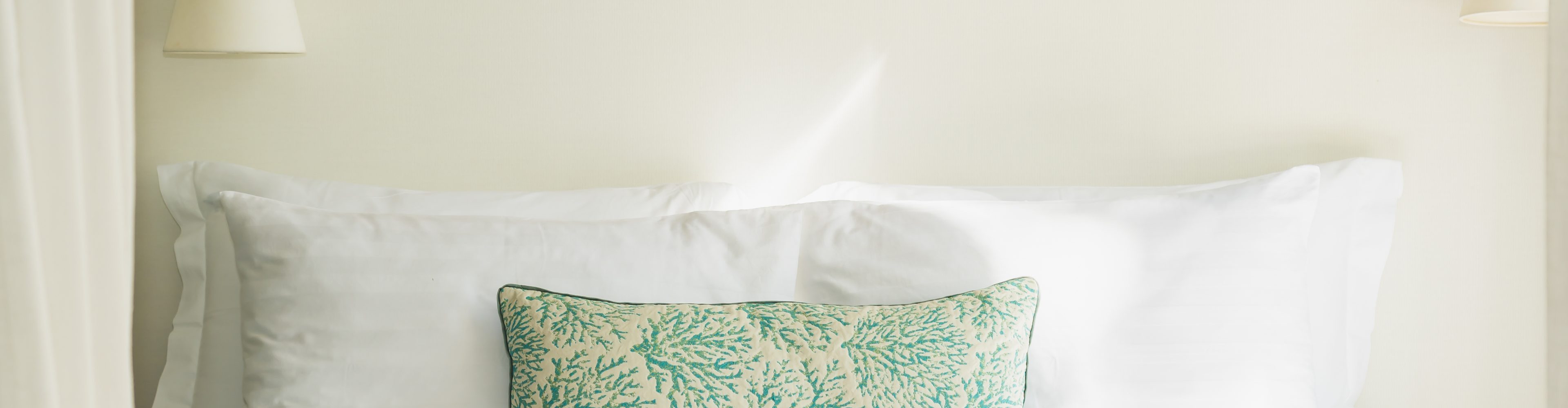 Hotel bed with white pillows and a patterned cushion