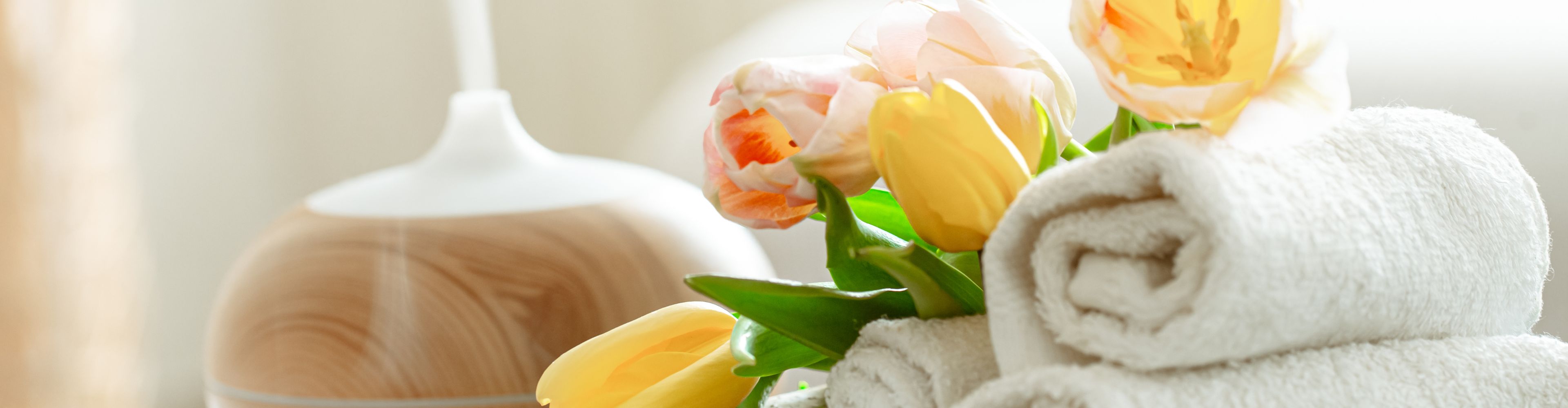 Rolled towels, tulips and an aroma diffuser in a spa