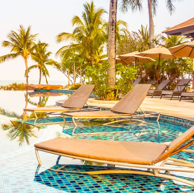 Resort pool with loungers under palm trees