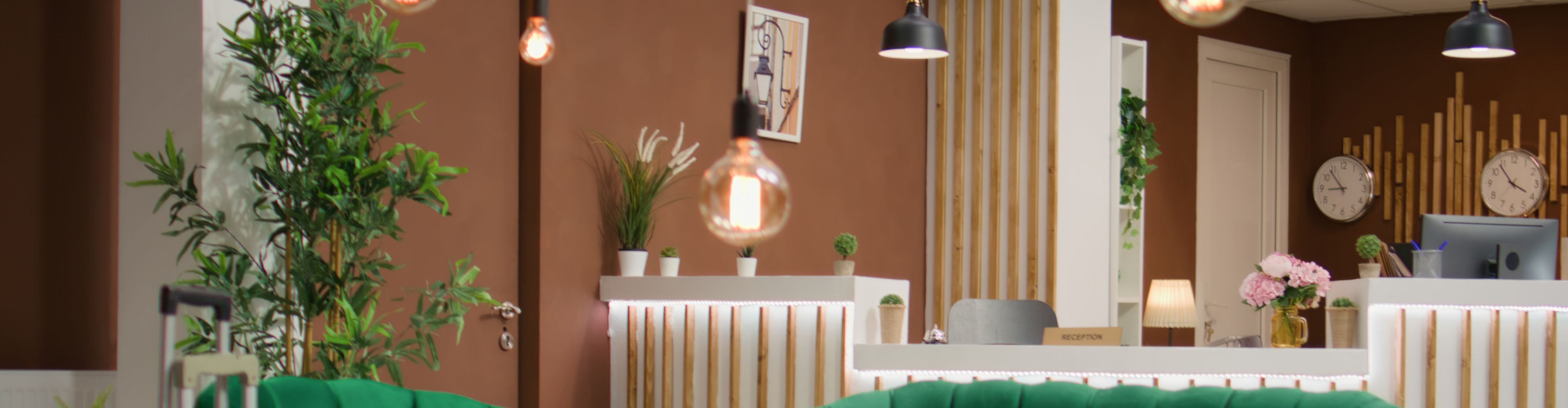Hotel lobby with reception desk, plants and wall clocks