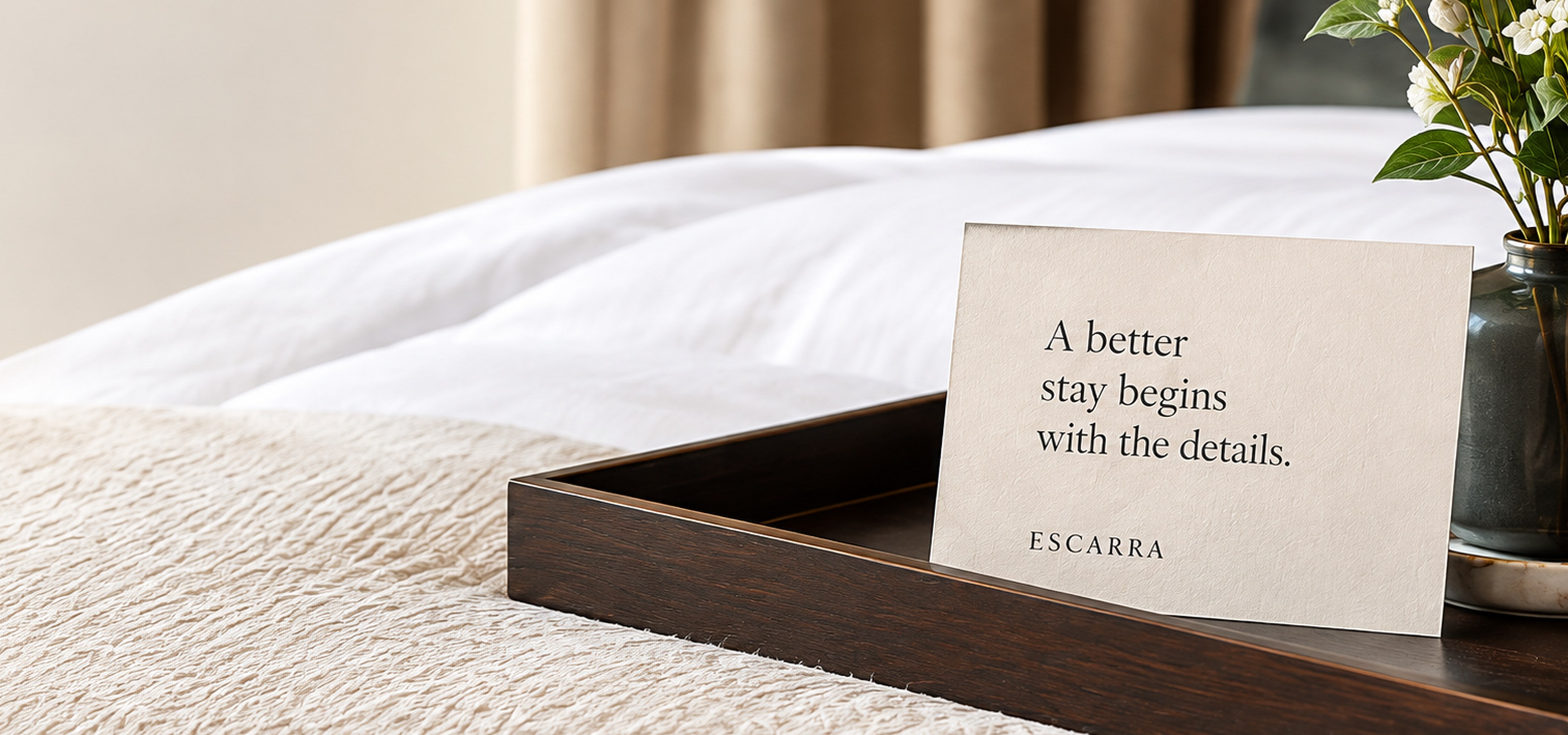 Hotel bed with an Escarra welcome card on a tray